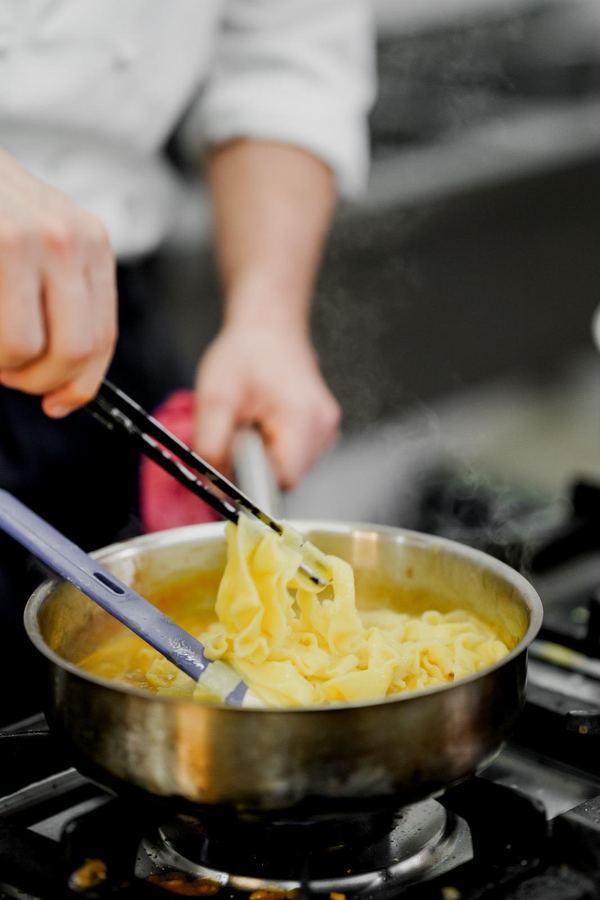 Chef tossing fresh pasta in the pan at Monaco